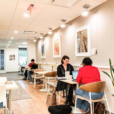 Members working at cafe tables under framed prints in the HAYVN Darien flex area
