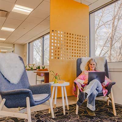 A member working from a sheepskin-draped armchair beside an amber perforated screen at HAYVN