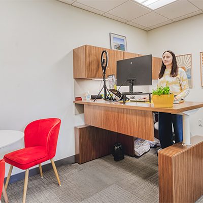 A medium HAYVN office with a wraparound timber desk, ring light, monitor and a red velvet armchair