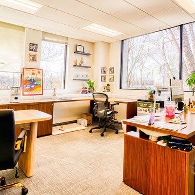 A private office at HAYVN with two windows, a mesh task chair and a walnut desk return